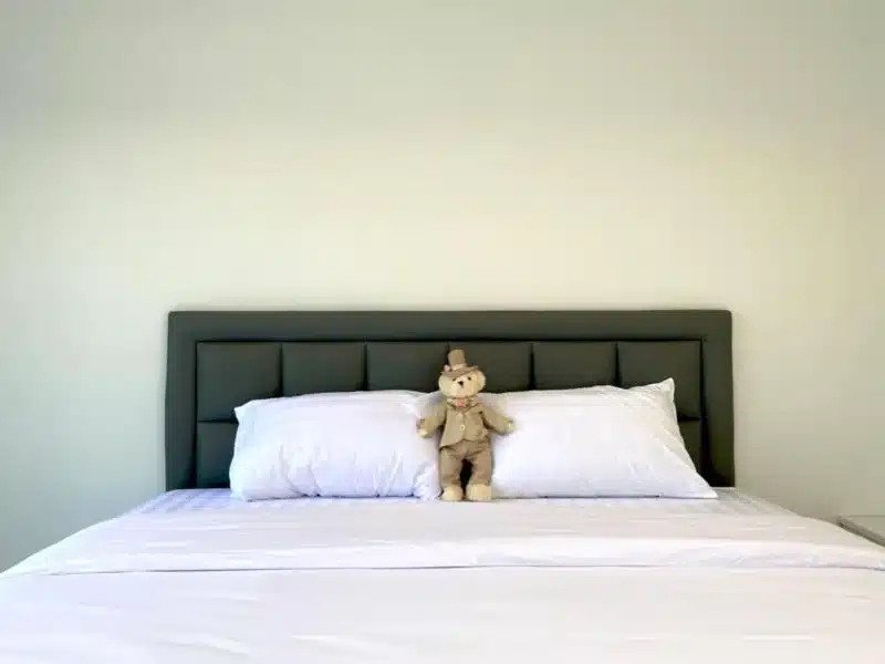 ที่พักกำแพงแสน ตุ๊กตาหมีนั่งอยู่บนเตียงสีขาว