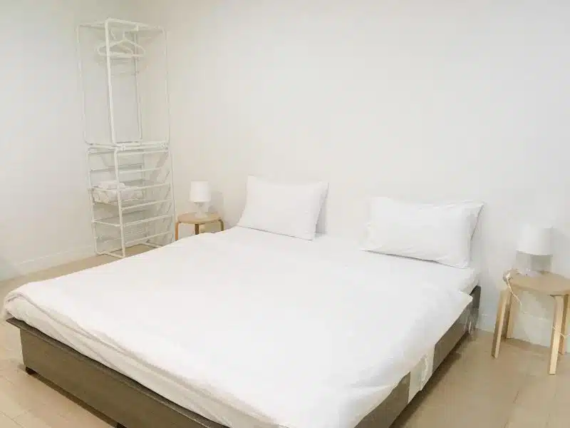 เตียงพร้อมผ้าปูที่นอนและหมอนสีขาวในห้อง รีสอร์ทใกล้สนามบินสุวรรณภูมิ
