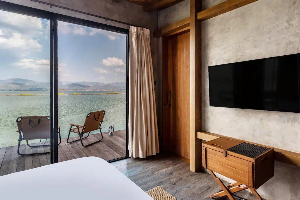 ห้องนอนที่ พูลวิลล่ากาญจนบุรี มีหน้าต่างบานใหญ่มองเห็นผืนน้ำ