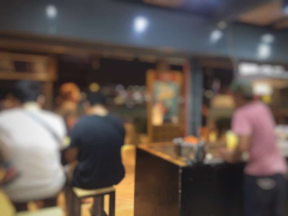 ภาพพร่ามัวของผู้คนที่ วัดเจ้าอามหมอลักษณ์ นั่งอยู่ในร้านอาหาร