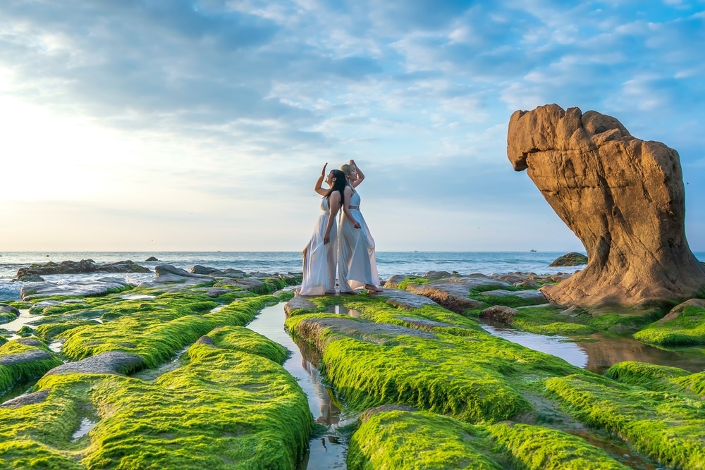 ผู้หญิง ที่เที่ยวเวียดนาม คนหนึ่งยืนอยู่บนก้อนหินที่ปกคลุมด้วยตะไคร่น้ำสีเขียว