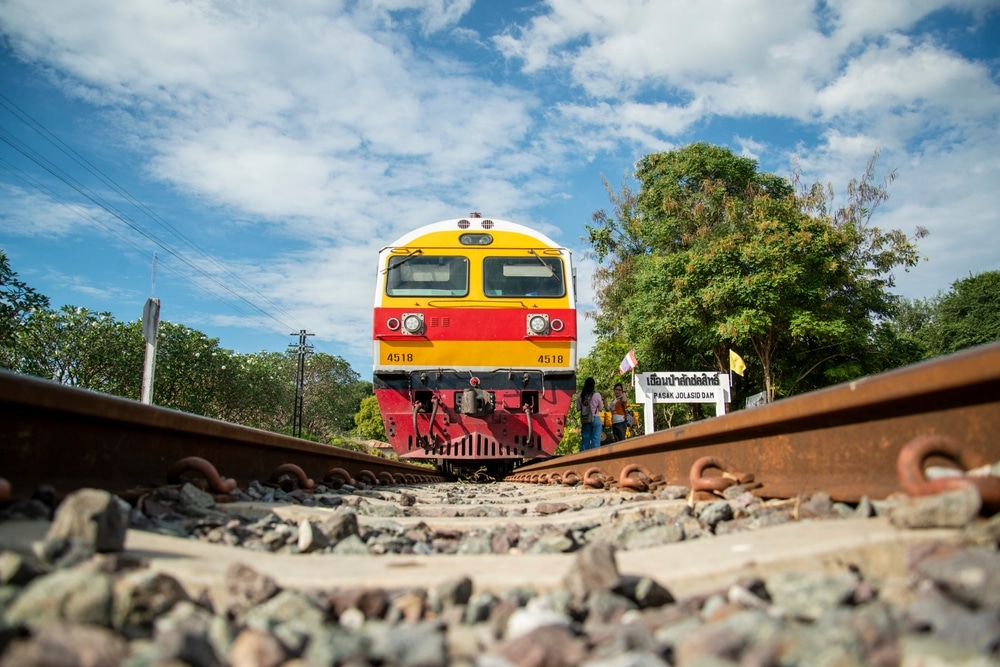 รถไฟสีเหลืองและสีแดงแล่นไปตามรางรถไฟ เที่ยวเขื่อนป่าสักชลสิทธิ์