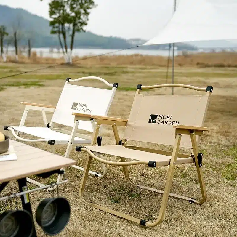เก้าอี้แค้มปิ้ง เก้าอี้สนามหญ้าสองสามตัวนั่งอยู่บนสนามหญ้าที่ปกคลุมด้วยหญ้า