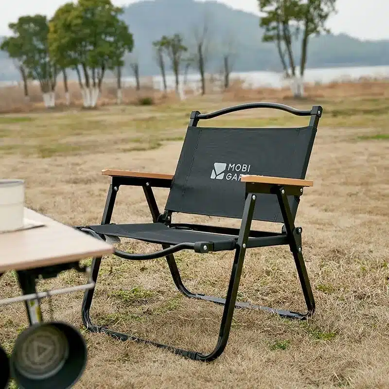เก้าอี้พับสีดำนั่งอยู่บนทุ่งหญ้าแห้ง เก้าอี้พับ