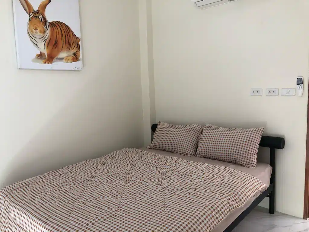 เตียงและภาพวาดเสือในห้องนอนที่โรงแรมจอมบึง ที่พักจอมบึง
