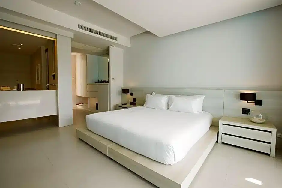 ที่พักแกลง เตียงสีขาวและโต๊ะข้างเตียงในห้องนอน