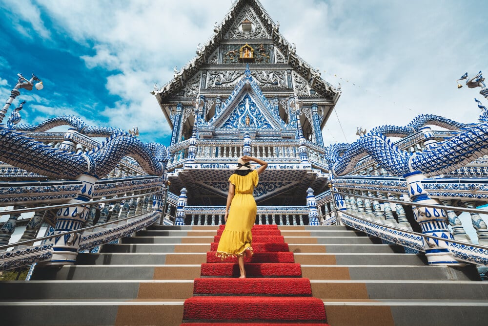 หญิงสาวในชุดสีเหลืองยืนอยู่บนบันไดพรมแดงในแหล่งท่องเที่ยวจันทบุรี จันทบุรีที่เที่ยว