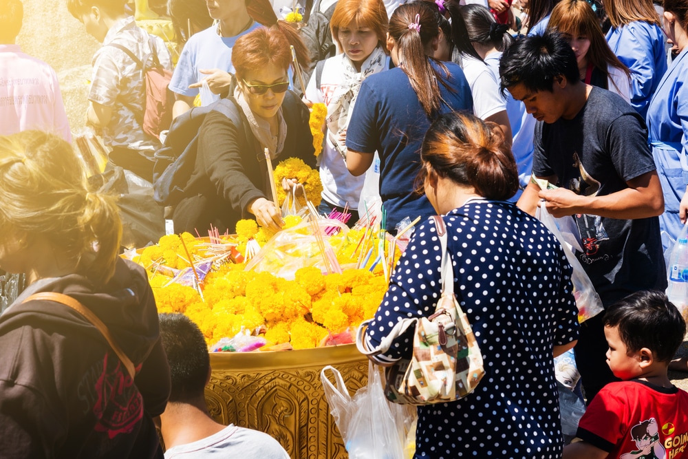 กลุ่มคนยืนล้อมโต๊ะด้วยดอกไม้สีเหลืองที่สถานที่ท่องเที่ยวในจันทบุรี เที่ยวจันทบุรี