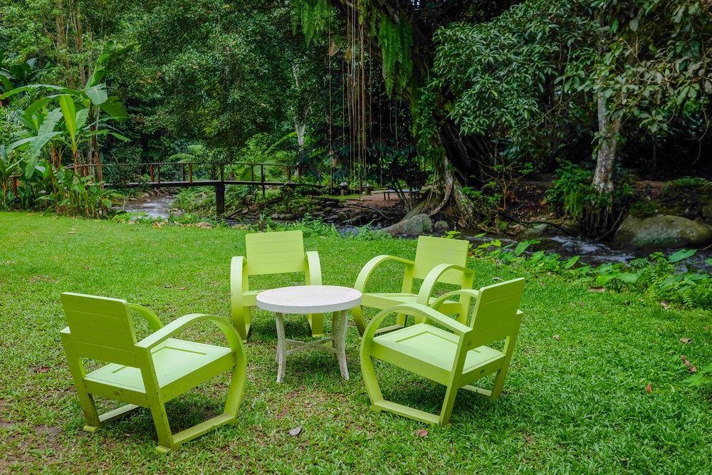 กลุ่มเก้าอี้สีเขียวและโต๊ะบนพื้นหญ้าในเชียงใหม่ สถานที่ท่องเที่ยวแม่กำปอง