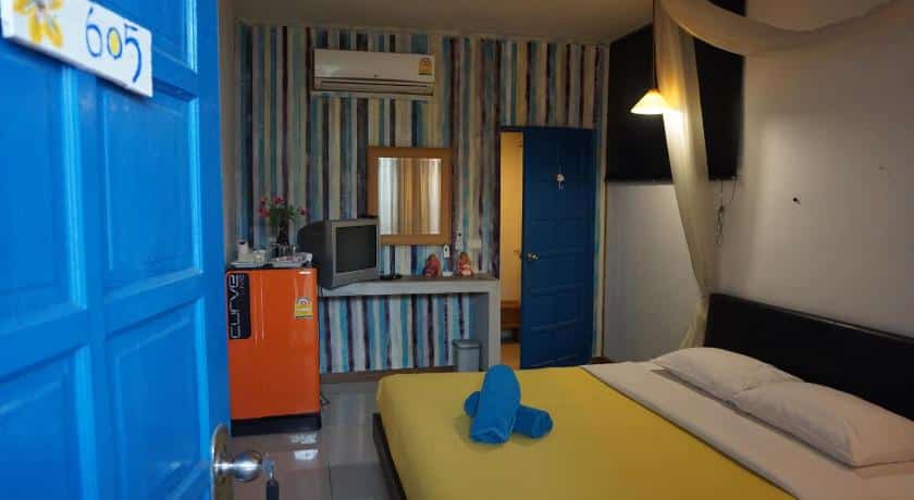 เตียงที่ทำอย่างประณีตและประตูสีฟ้าในห้องนอนที่บ้านพักตากอากาศริมแม่น้ำในราชบุรี