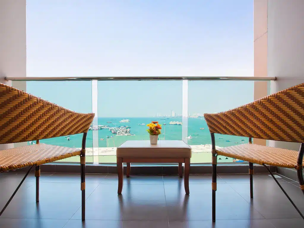 เก้าอี้สองตัวและโต๊ะหน้าหน้าต่างบานใหญ่ที่มองเห็นเมืองพัทยา ที่เที่ยวพัทยาใต้