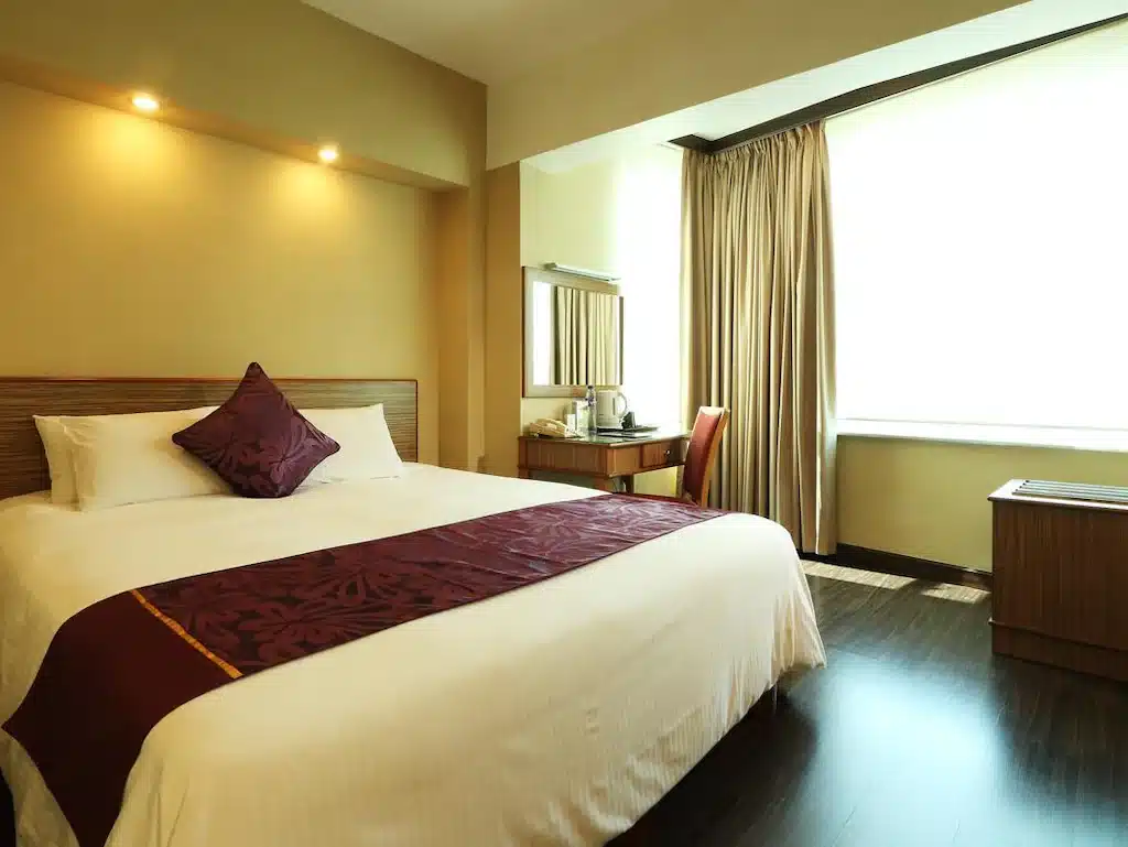 ห้องพักในโรงแรมที่มีเตียงขนาดใหญ่และโต๊ะทำงานในสถานที่ท่องเที่ยวราชบุรี ที่เที่ยวฮ่องกง
