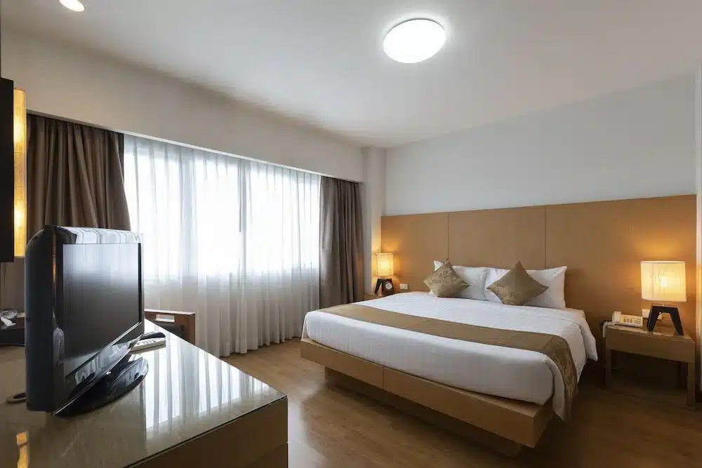 เตียงที่ทำอย่างประณีตและทีวีจอแบนในห้องพักโรงแรมในราชบุรี