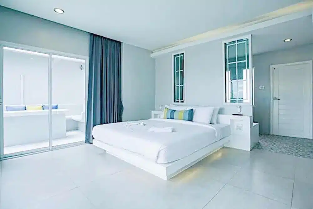 เตียงสีขาวและผ้าม่านสีน้ำเงินในห้องนอนใกล้แม่น้ำในจังหวัดราชบุรี