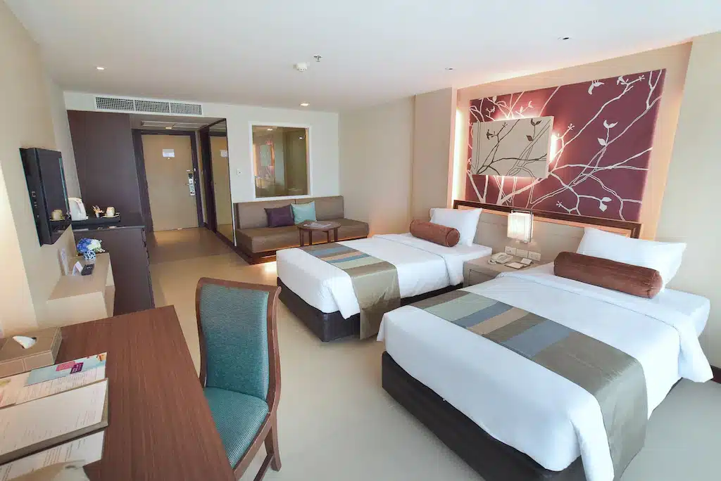ห้องพักในโรงแรมที่มีสองเตียงและโต๊ะทำงานในสถานที่ท่องเที่ยวพิษณุโลก