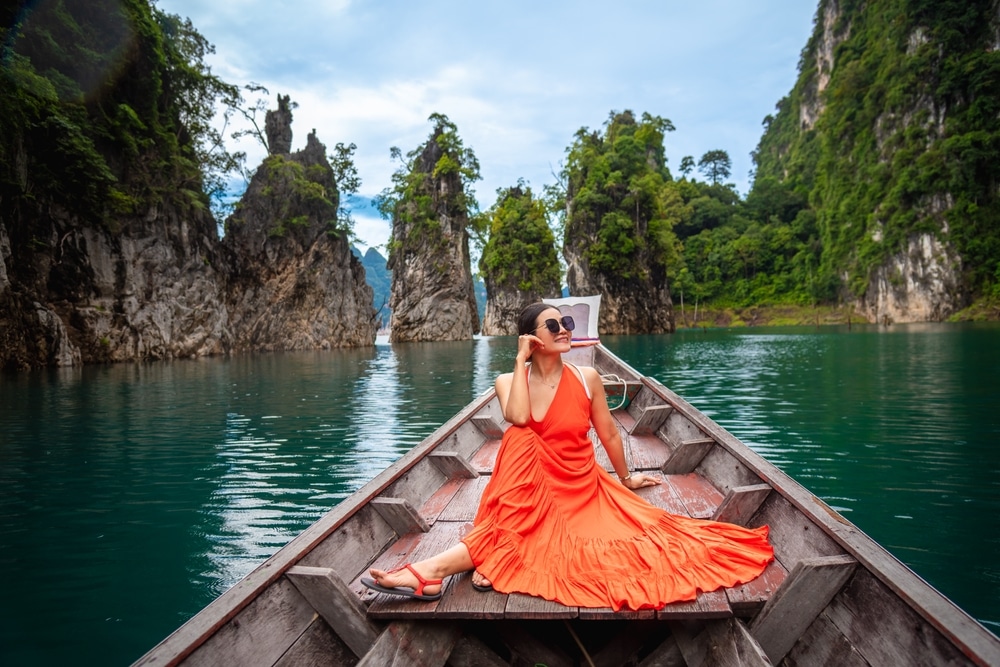 ผู้หญิงชุดส้มนั่งอยู่บนเรือ ที่เที่ยวเขาสก