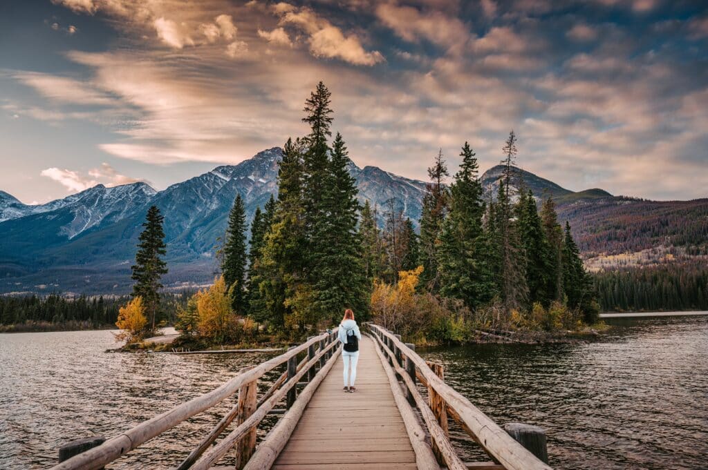 ผู้หญิงกำลังเดินข้ามสะพานไม้เหนือทะเลสาบในแหล่งท่องเที่ยวของนคร ที่เที่ยวอเมริกา
