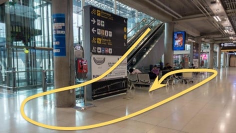 บันไดเลื่อนสนามบินที่มีลูกศรสีเหลืองชี้ขึ้น