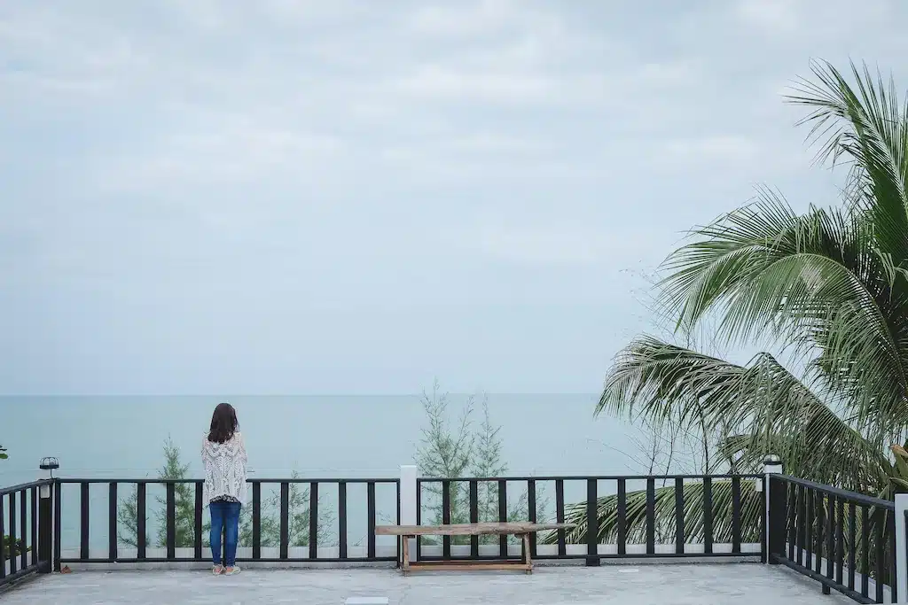 ผู้หญิงกำลังชื่นชมทะเลจากระเบียงที่รีสอร์ทริมทะเลในจังหวัดระยอง โรงแรมท่าศาลา