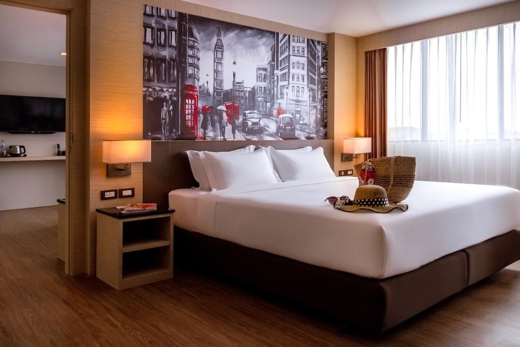 เตียงนอนในห้องพักโรงแรมพร้อมภาพขนาดใหญ่บนกำแพงที่หาดหาดแม่พิมพ์ ที่พักพัทยาใต้