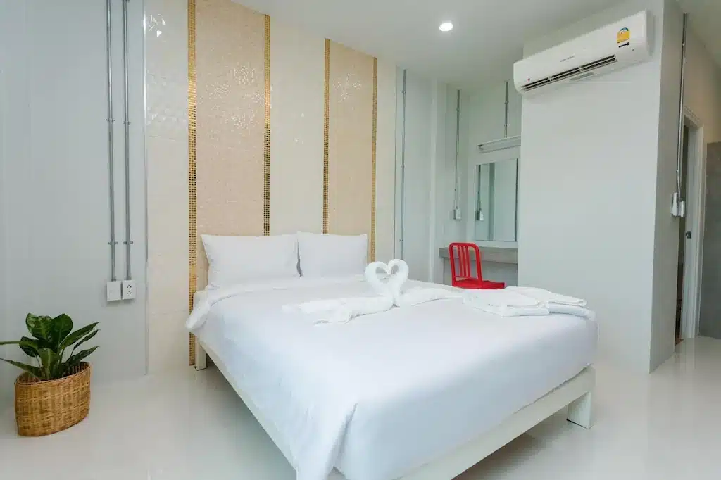 ห้องพักริมชายหาดที่มีเตียงสีขาวและเก้าอี้สีแดงในจังหวัดระยอง โรงแรมท่าศาลา