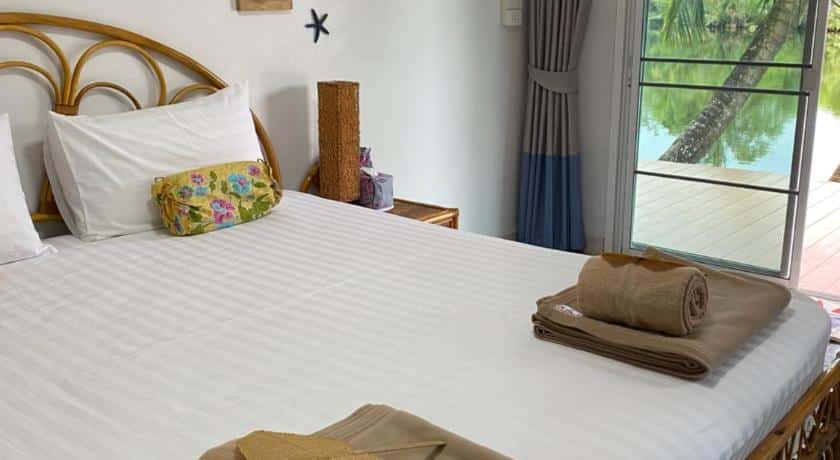 ห้องนอนพร้อมเตียง ผ้าเช็ดตัว และวิวน้ำ ที่พักตะกั่วป่า