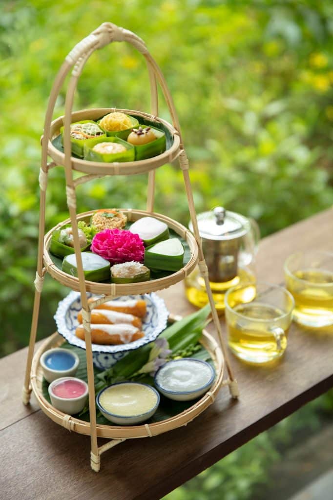 โต๊ะไม้แสดงถาดสามชั้นประดับด้วยชาและกาน้ำชาในจังหวัดนครปฐม สถานที่ท่องเที่ยวยอดนิยมของประเทศไทย