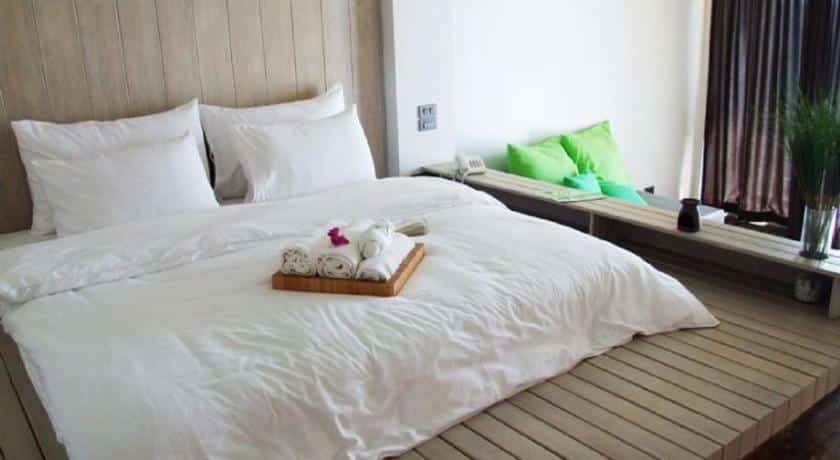 เตียงสีขาวในห้องปูด้วยพื้นไม้ ดอยเลา ที่พัก ที่พักระยองติดทะเล