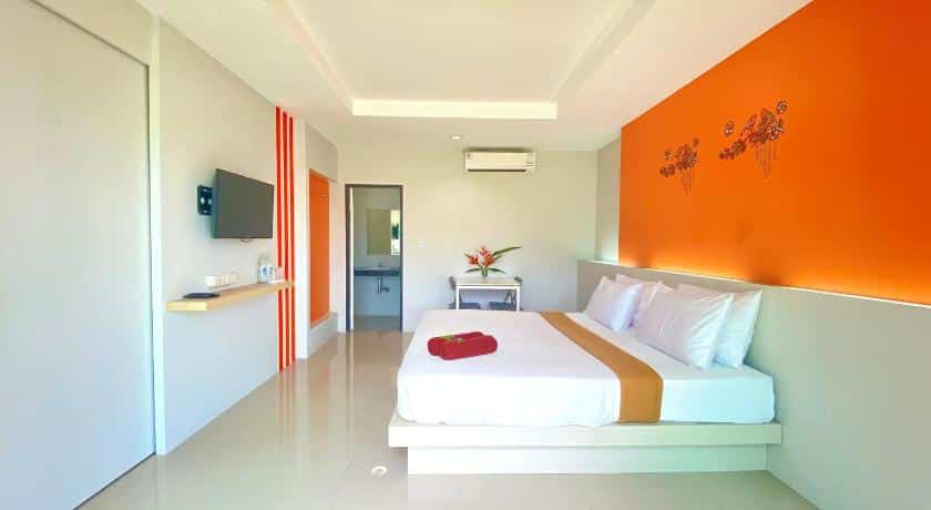 ห้องที่มีผนังสีส้มและเตียงสีขาว ที่พักตะกั่วป่า