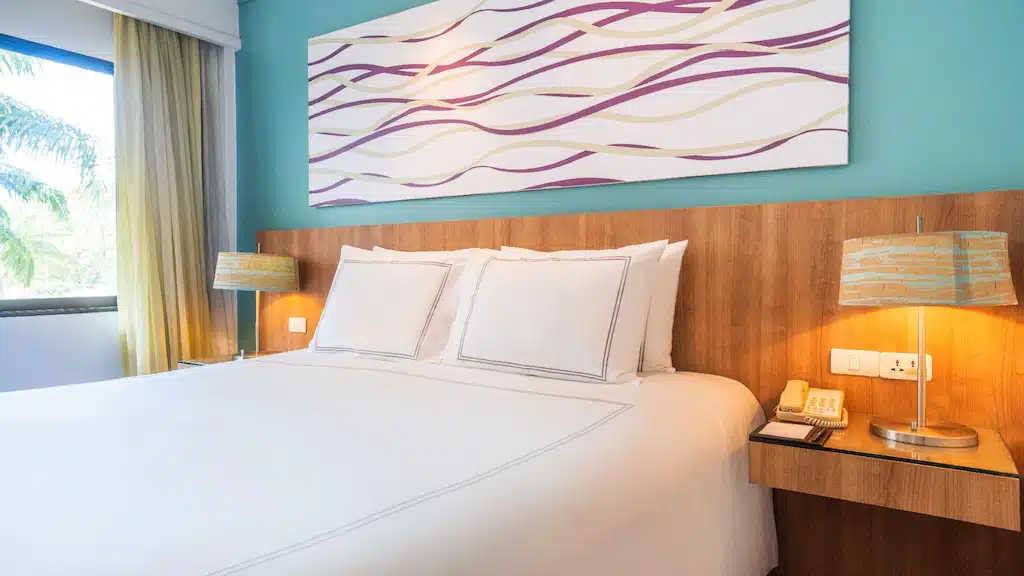 เตียงในห้องพักโรงแรมที่มีผนังสีน้ำเงินและภาพวาดบนผนังที่ โรงแรมในภูเก็ต