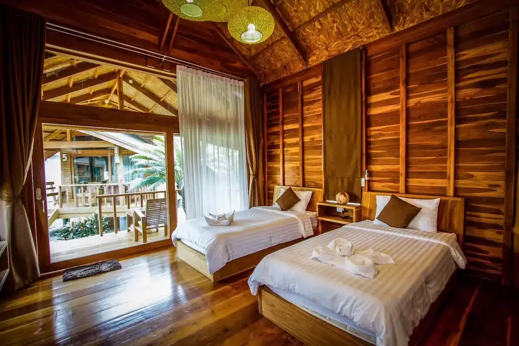 เตียงนอน 2 เตียงในรีสอร์ทบนดอยกะลาที่มีผนังไม้ ที่พักติดทะเลระยอง