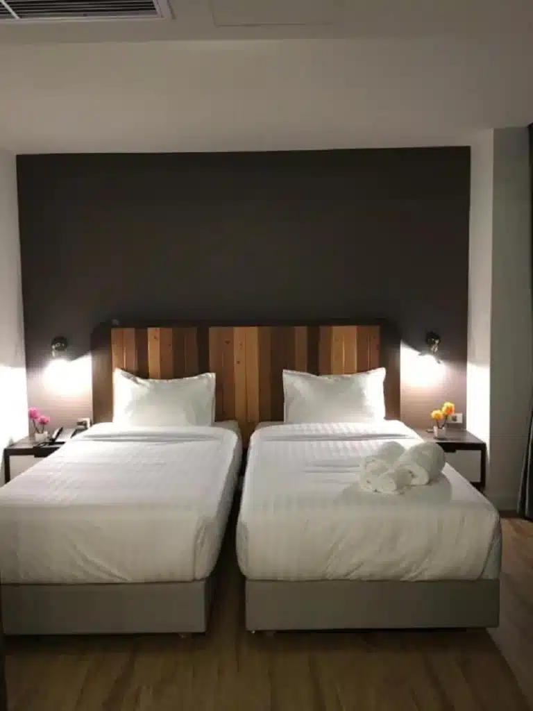 เตียงสองเตียงในห้องพักของโรงแรมที่มีพื้นไม้ นครปฐมที่เที่ยว