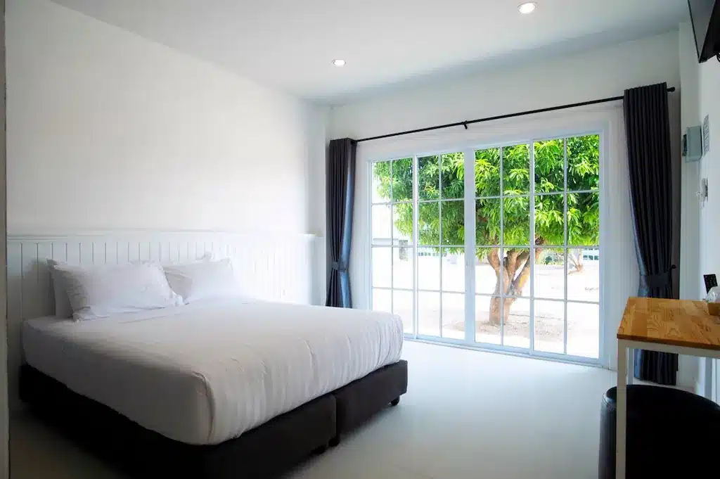 ห้องที่มีเตียงสีขาวและประตูกระจกบานเลื่อนในพระนอนวัดโพธิ์