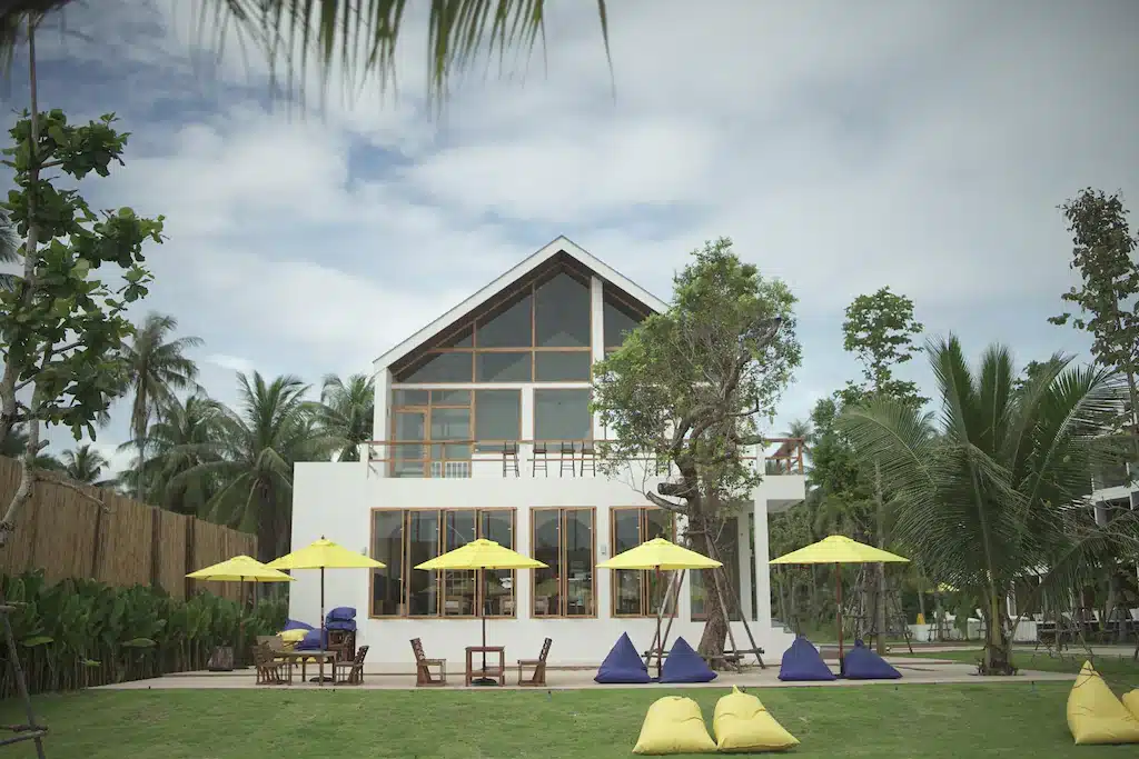 บ้านสีขาวพร้อมร่มสีเหลืองด้านหน้า ตั้งอยู่ใกล้ทะเลในจังหวัดระยอง ที่พักท่าศาลา