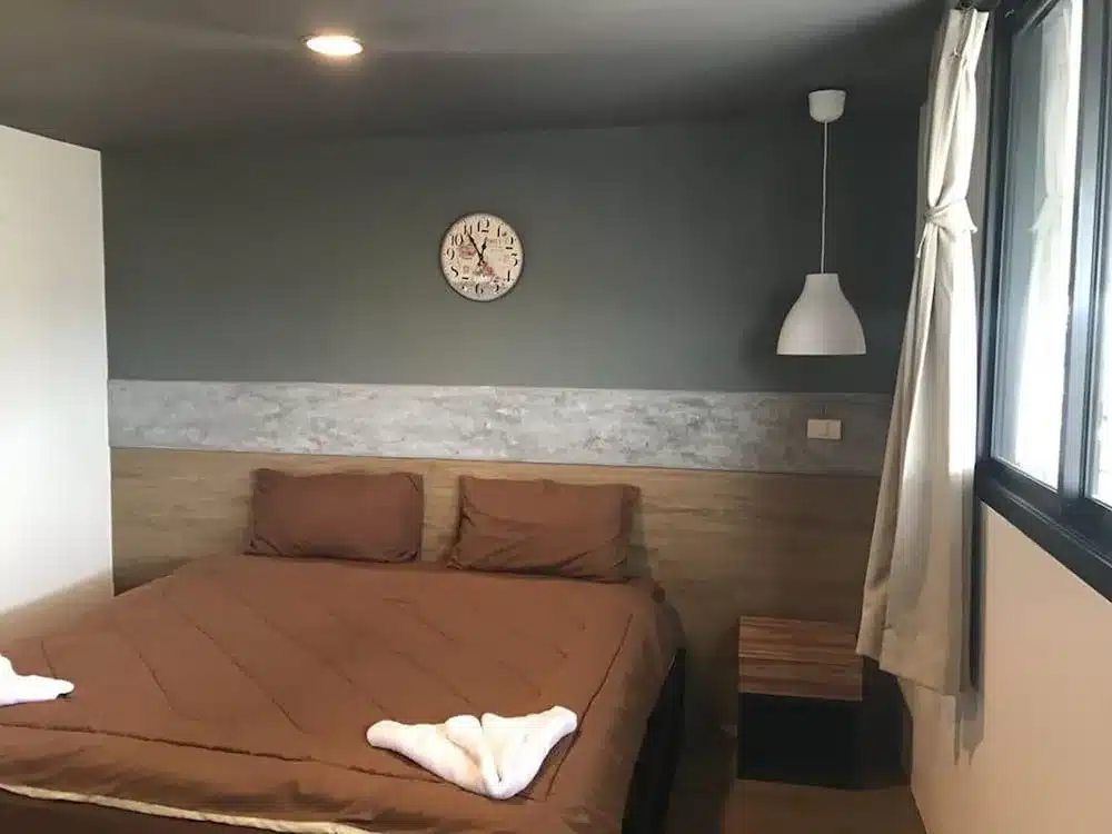 ห้องนอนเล็กๆ ที่พักตะกั่วป่า ที่มีเตียงสีน้ำตาลและนาฬิกา