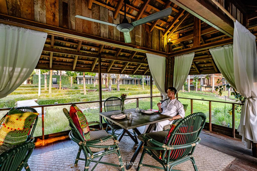 ผู้หญิงคนหนึ่งเพลิดเพลินกับทัศนียภาพอันงดงามจากโต๊ะบนระเบียงไม้ของวีรันดา ไฮ รีสอร์ท เชียงใหม่ Veranda High Resort Chiangmai