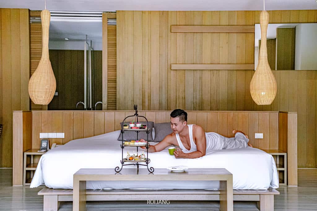 วีรันดา ไฮ รีสอร์ท เชียงใหม่ ให้บริการห้องพักหรูหราในห้องไม้ที่มีผู้ชายนอนอยู่บนเตียง ที่พักเชียงใหม่ธรรมชาติ