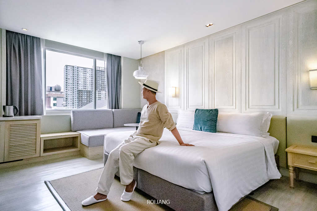 ผู้ชายกำลังนั่งอยู่บนเตียงใน Health Land Resort & Spa Pattaya