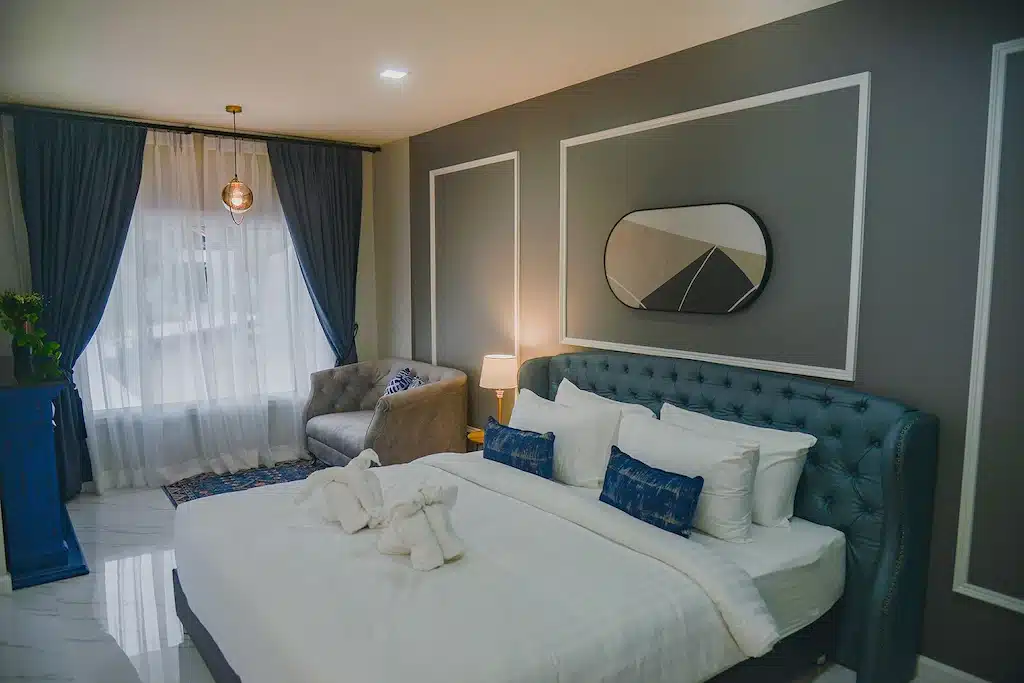 เตียงในห้องที่โรงแรม Left Station ที่มีผนังสีน้ำเงินและผ้าปูที่นอนสีขาว ที่พักช้างกลาง