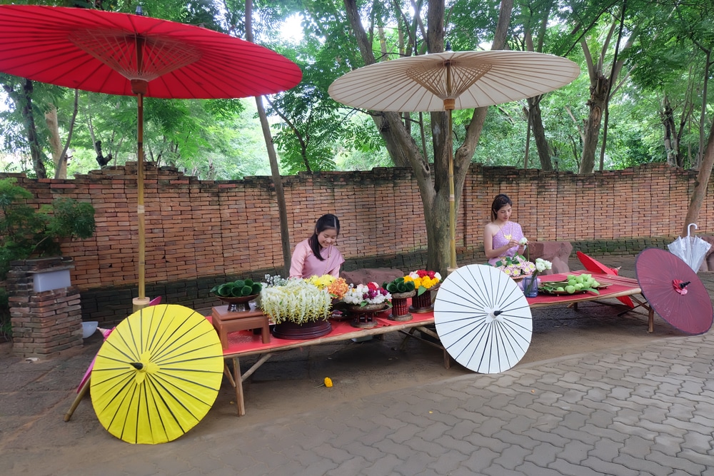 ผู้หญิงกำลังขายดอกไม้ที่เที่ยวนครนายกภายใต้ร่มสีแดง เที่ยวภาคกลาง เที่ยวภาคกลาง