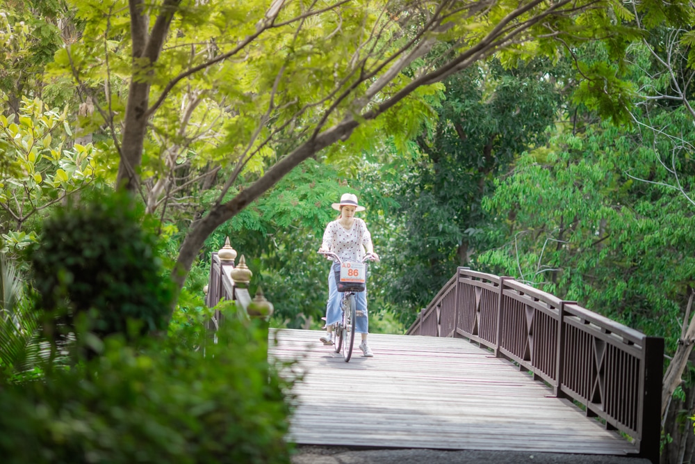 ผู้หญิงขี่จักรยานบนสะพานไม้ในสถานที่ท่องเที่ยวนครนายก ที่เที่ยวภาคกลาง