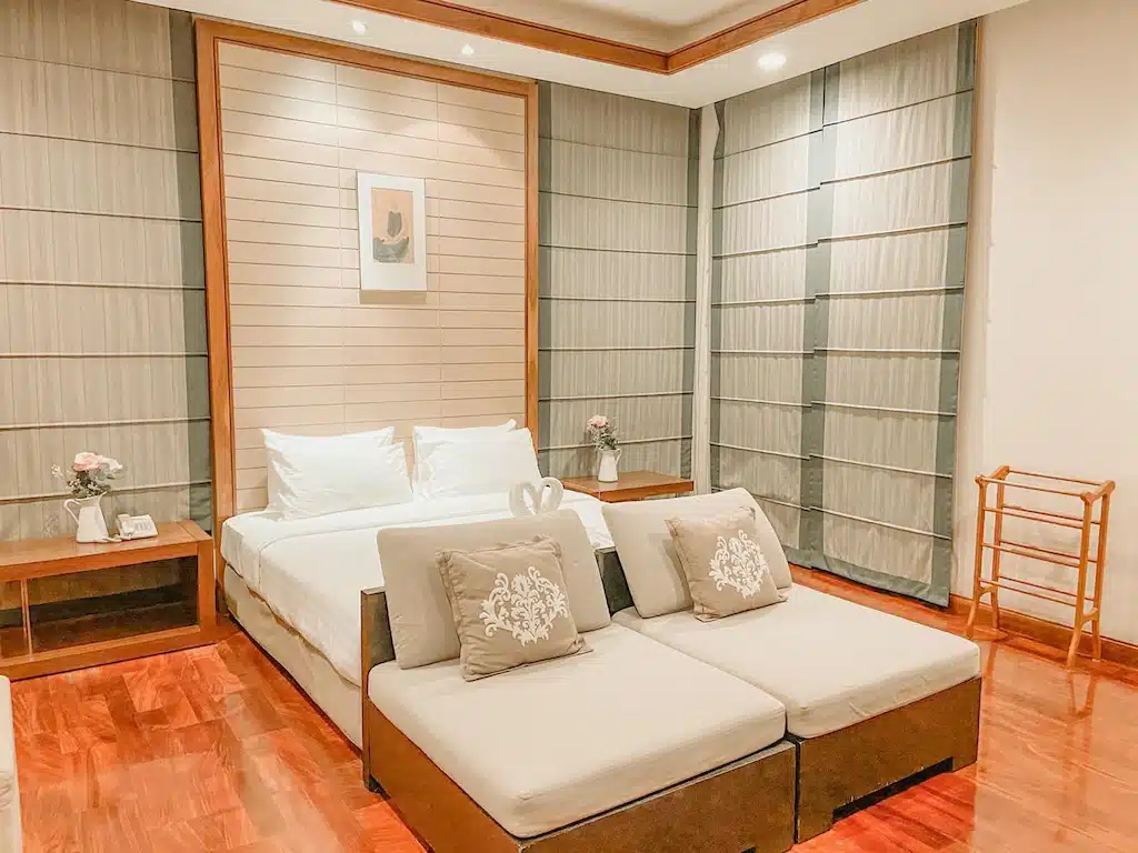 ห้องนอนที่ได้รับแรงบันดาลใจจากวัดสมานที่มีพื้นไม้และเตียงนอน วัดเขาสามมุข