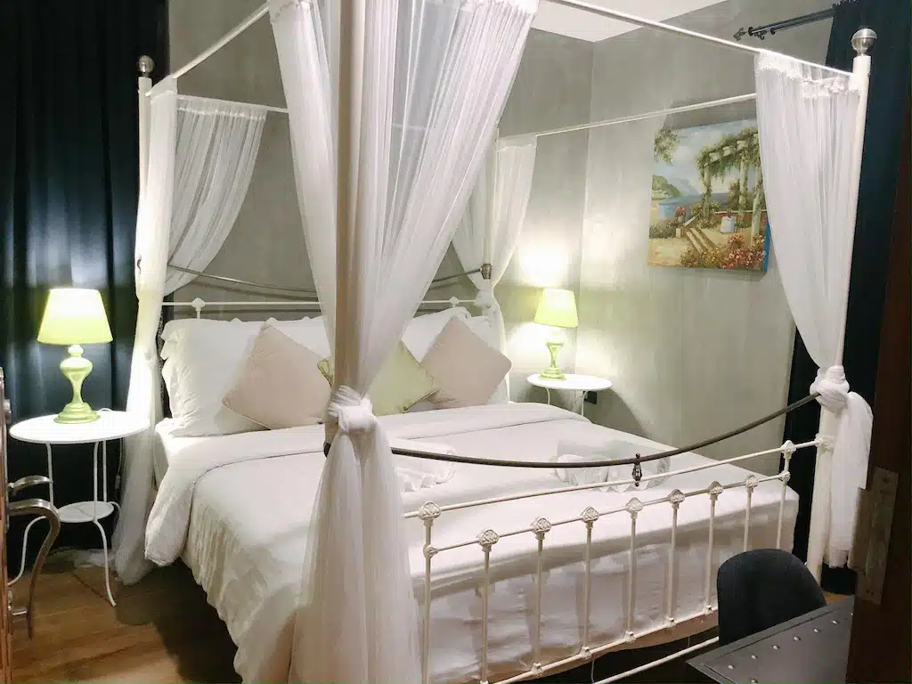 เตียงกระโจมสีขาวในห้องที่มีโคมไฟ ที่เที่ยวอัมพวา