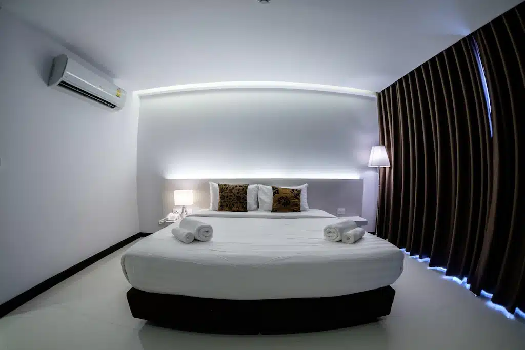 เตียงสีขาวในห้องที่มีพัดลมเพดาน เที่ยวสิงห์บุรี