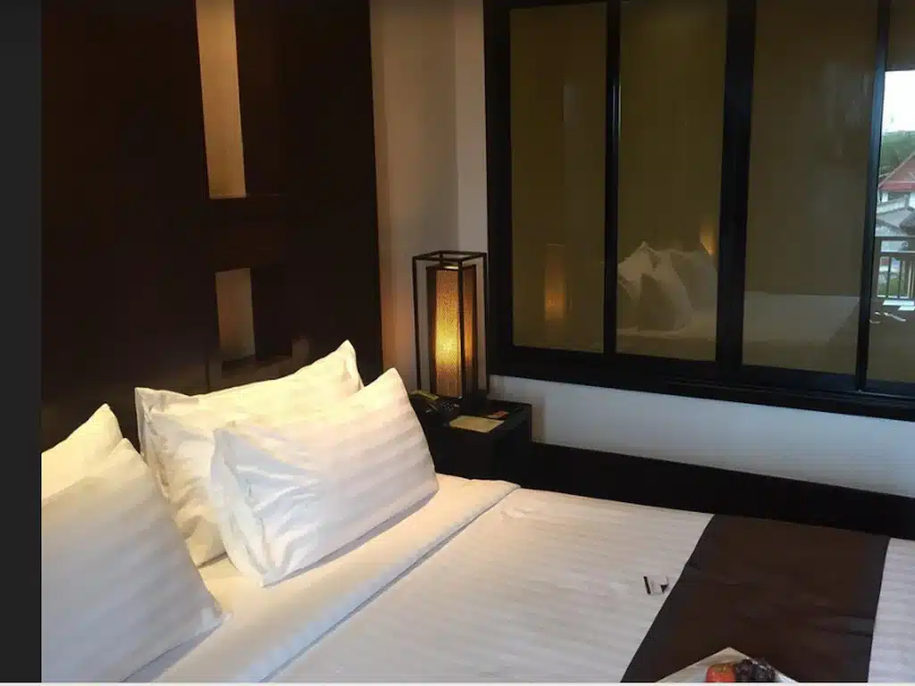 ห้องพักในโรงแรมที่มีโคมไฟข้างเตียง รูปพระพุทธชินราช