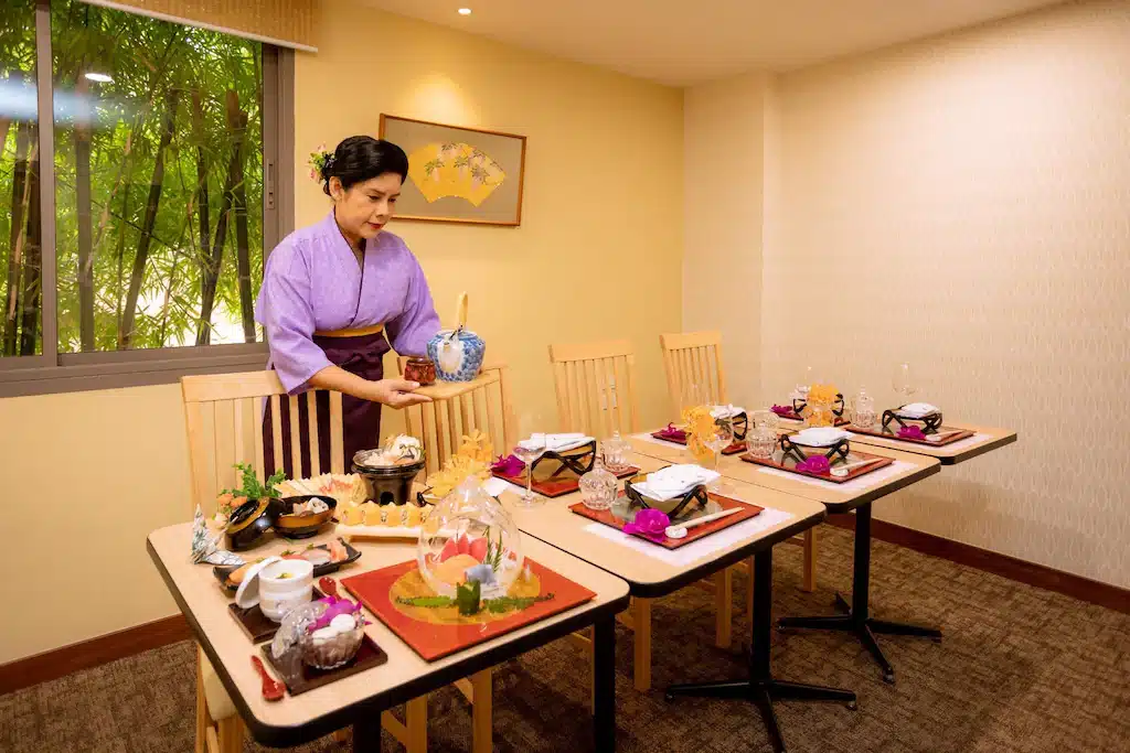 ผู้หญิงคนหนึ่งกำลังจัดโต๊ะอาหารที่โรงแรมศรีราชา โรงแรมศรีราชา