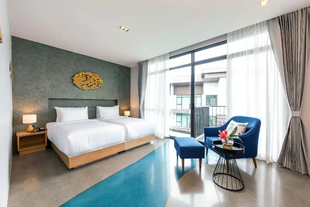 ห้องพักในโรงแรมที่มีเตียง 2 เตียงและเก้าอี้สีน้ำเงินตั้งอยู่ใกล้กับวัดบางขุนเทียน วัดบางกุ้ง สมุทรสงคราม