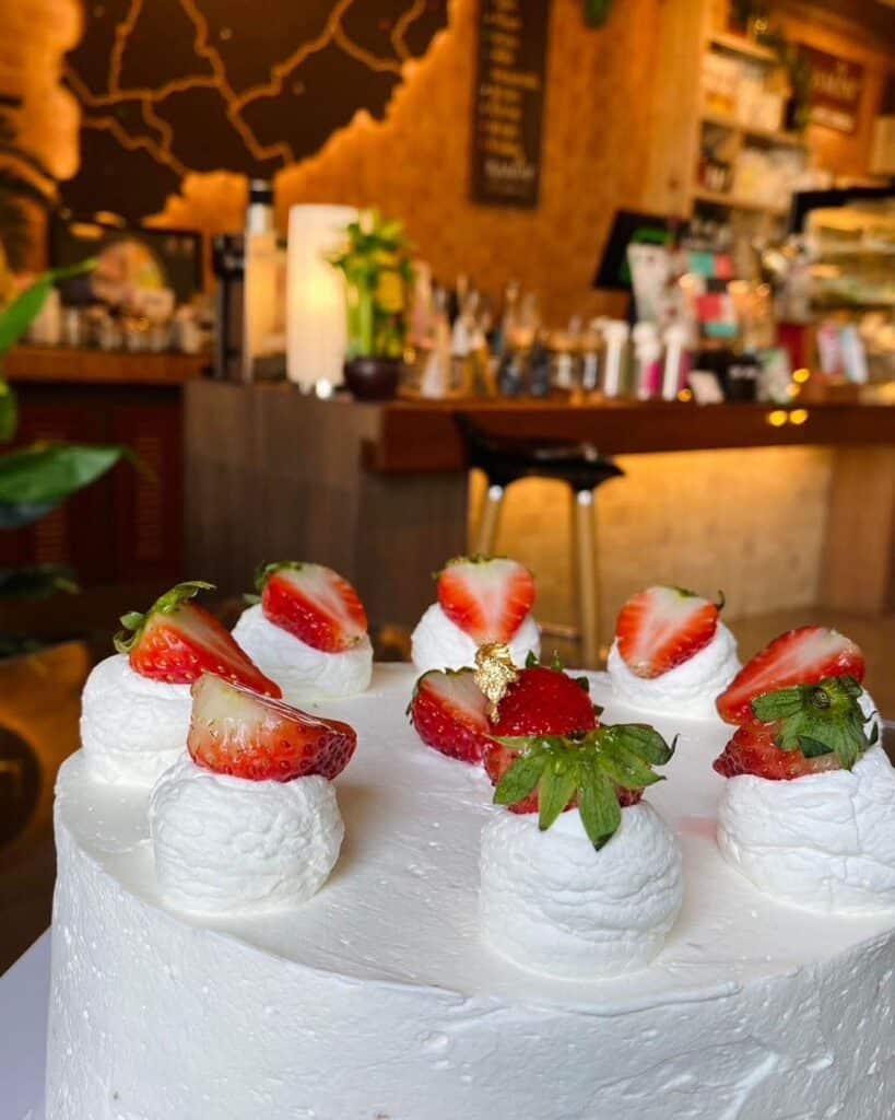 สถานที่ท่องเที่ยวสุโขทัย : เค้กสีขาวที่มีสตรอเบอรี่วางอยู่ที่โต๊ะในเมือง อุตรดิตถ์ที่เที่ยว