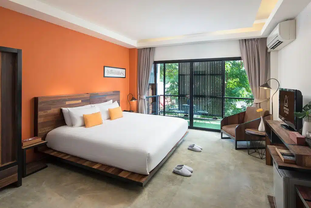 ห้องพักในโรงแรมที่มีผนังสีส้มและเตียงขนาดใหญ่ อัมพวาที่เที่ยว