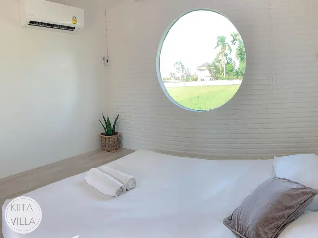 หน้าต่างทรงกลมในที่พักภูเรือล้อมรอบด้วยเตียงสีขาว ที่พักบ้านโป่ง